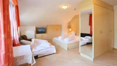 a living room with two beds and a mirror at Pension Alpenhof B&B in Colle Isarco