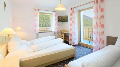 a hotel room with two beds and a window at Pension Alpenhof B&B in Colle Isarco