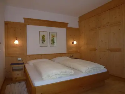 a bedroom with a bed with wooden walls and two lights at Cedepuent de Sot in Selva di Val Gardena