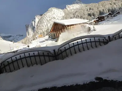 a house covered in snow in front of a mountain at Cedepuent de Sot in Selva di Val Gardena
