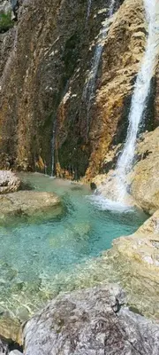 a waterfall on the side of a mountain with blue water at Cedepuent de Sot in Selva di Val Gardena