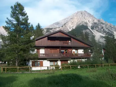 a large building with a mountain in the background at Villa Istria Apartment in San Vito di Cadore