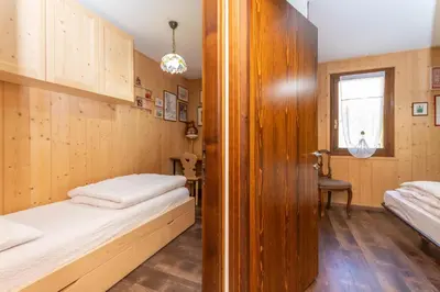 a small room with two beds and a window at Chalet Baranci in Pozza di Fassa