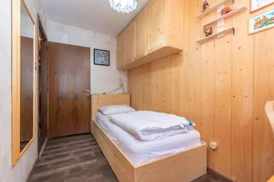 a small bed in a room with wooden walls at Chalet Baranci in Pozza di Fassa