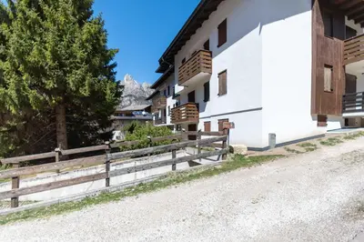a road next to a white building with a fence at Chalet Baranci in Pozza di Fassa