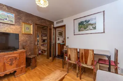 a living room with a television and a table and chairs at Chalet Baranci in Pozza di Fassa