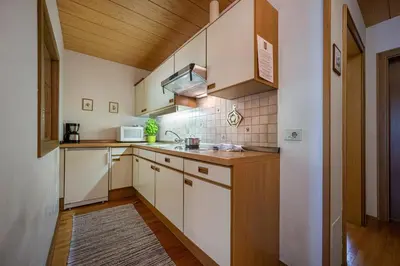 a kitchen with white cabinets and a wooden ceiling at Panorama Apartments Walter in Ortisei
