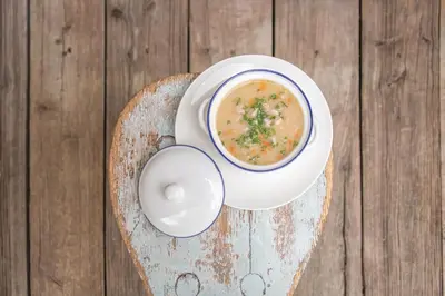 a bowl of soup on a wooden table at Ciasa Somuer in San Vigilio Di Marebbe