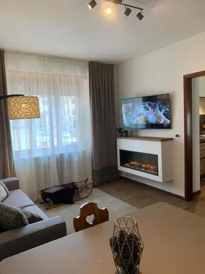 a living room with a fireplace and a tv on a wall at DHome in Agordo