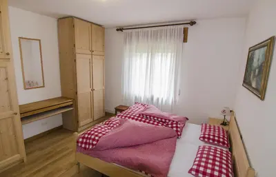 a bedroom with a bed with red and white sheets at Ciasa Nina in San Vito di Cadore