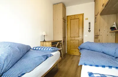 a bedroom with two beds with blue and white pillows at Ciasa Nina in San Vito di Cadore