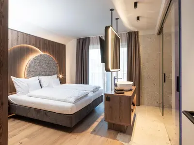 a hotel room with a bed and a mirror at Corones Suites - Dolomites Residence in Valdaora