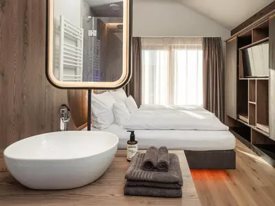 a bathroom with a white tub and a bed at Corones Suites - Dolomites Residence in Valdaora