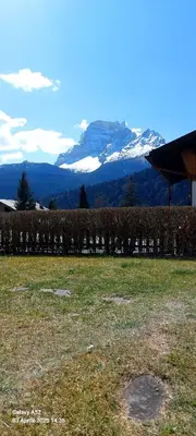 a field with a snow covered mountain in the background at Villa Serena in San Vito di Cadore