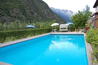 a large blue swimming pool with two chairs and umbrellas at Hotel Mondschein in Plaus