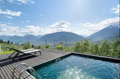 a swimming pool with a bench on a deck with mountains at Dahoam - Vistasuite in Schenna