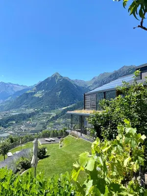 a house on a hill with mountains in the background at Dahoam - Vistasuite in Schenna