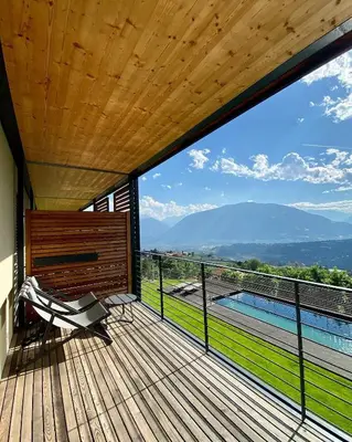 a wooden deck with a bench and a swimming pool at Dahoam - Vistasuite in Schenna