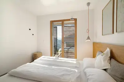 a white bedroom with a bed and a window at Dahoam - Panoramasuite in Schenna