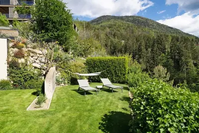 a garden with two chairs and a table in the grass at Dahoam - Panoramasuite in Schenna
