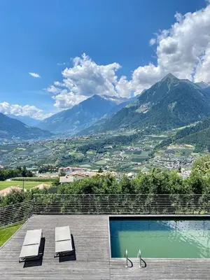 two people walking on a deck with a view of mountains at Dahoam - Panoramasuite in Schenna