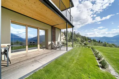 a house with a deck with a view of the mountains at Dahoam - Gardensuite R in Schenna