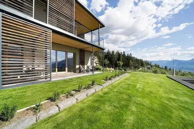 a house on a hill with a green lawn at Dahoam - Gardensuite R in Schenna