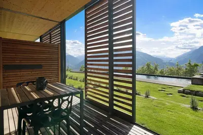 a porch with a wooden bench and a large window at Dahoam - Gardensuite L in Schenna