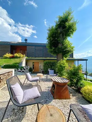 a patio with chairs and a table and a building at Dahoam - Gardensuite L in Schenna