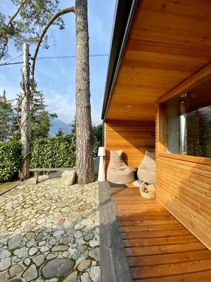 a wooden house with a tree on a patio at Dahoam - Gardensuite L in Schenna