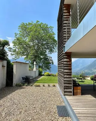 a house with a patio with a table and a tree at Dahoam - Panoramchalet in Schenna