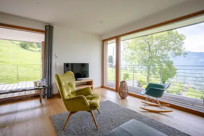 a living room with a large window and a chair at Dahoam - Panoramchalet in Schenna