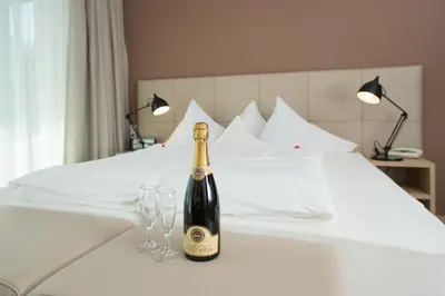 a bottle of champagne sitting on a bed with two glasses at Seeberg Garni Hotel in Caldaro