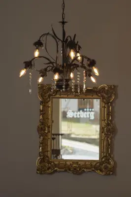 a mirror with a chandelier hanging from a wall at Seeberg Garni Hotel in Caldaro