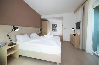 a bedroom with a white bed and a television at Seeberg Garni Hotel in Caldaro
