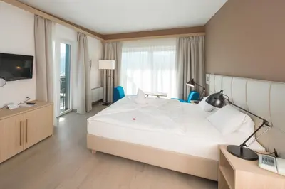 a bedroom with a large white bed and a television at Seeberg Garni Hotel in Caldaro
