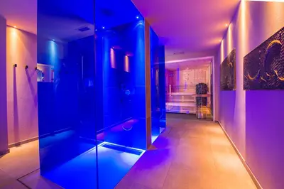 a bathroom with a glass shower with purple lighting at Seeberg Garni Hotel in Caldaro