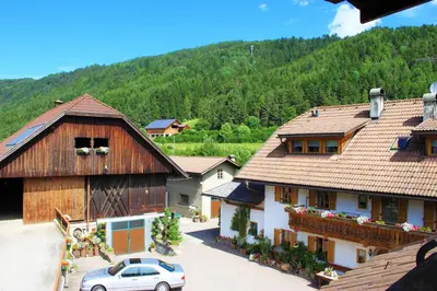 a group of buildings with a car parked in a parking lot at Haus Ploner - Pichlerhof in Chienes