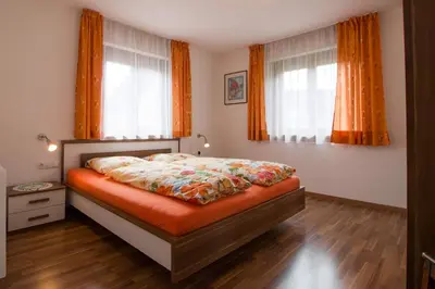 a bedroom with a bed with orange curtains at Haus Ploner - Pichlerhof in Chienes
