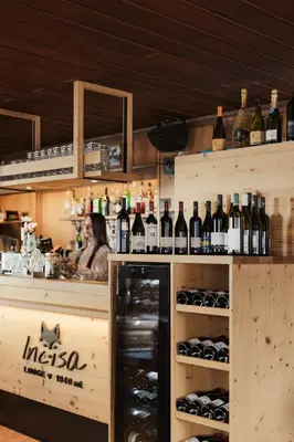 a woman behind a counter with bottles of wine at Incisa Lodge in Corvara in Badia