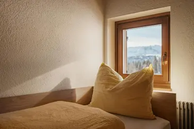a bed with pillows sitting in a room with a window at Incisa Lodge in Corvara in Badia