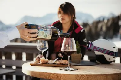 a woman pouring a glass of wine on a table at Incisa Lodge in Corvara in Badia