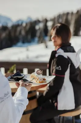a person holding a plate of food on a table at Incisa Lodge in Corvara in Badia