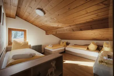 two beds in a room with wooden ceilings at Incisa Lodge in Corvara in Badia