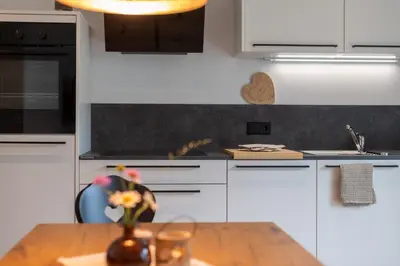 a kitchen with white cabinets and a wooden table at Haus Karin living in Brixen