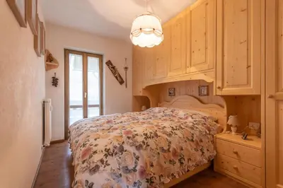 a bedroom with a bed and wooden cabinets at Casa Sot Croze in Pozza di Fassa