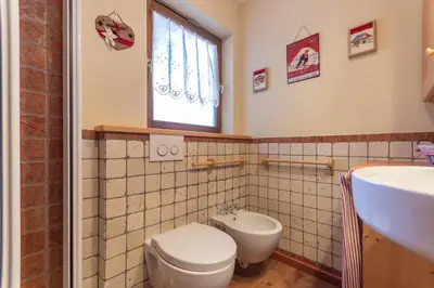 a bathroom with a toilet and a sink at Casa Sot Croze in Pozza di Fassa