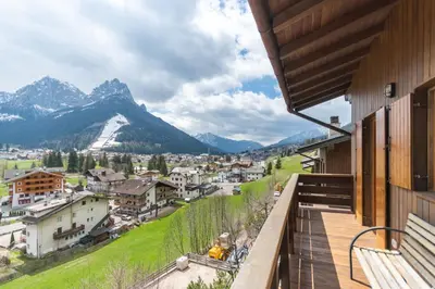 a balcony with a view of a town and mountains at Casa Sot Croze in Pozza di Fassa