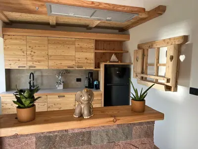 a kitchen with wooden cabinets and a black refrigerator at La Casa del Zio Bepi in Bedollo