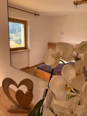a vase with white flowers in front of a mirror at La Casa del Zio Bepi in Bedollo